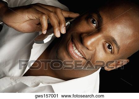 Stock Image - Portrait of a young man using a mobile phone and smiling. Fotosearch