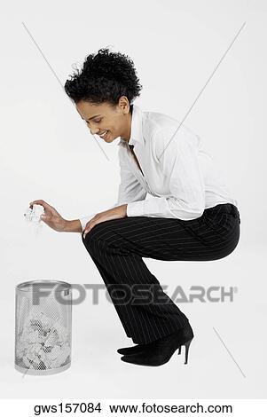 Side profile of a businesswoman throwing a crumpled sheet of paper into a wastepaper basket View Large Photo Image Picture - Side profile of a businesswoman throwing a crumpled sheet of paper into a wastepaper basket. Fotosearch