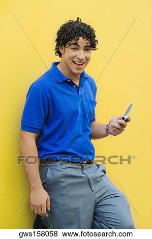 Stock Photo - Portrait of a young man holding a mobile phone and smiling. Fotosearch