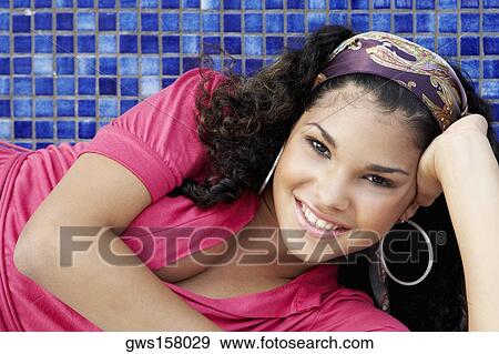 Stock Photo - Portrait of a young woman lying on her side and smiling. Fotosearch