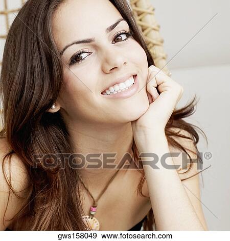 Portrait of a young woman smiling with her hand on her chin View Large Photo Image Stock Photo - Portrait of a young woman smiling with her hand on her chin. Fotosearch
