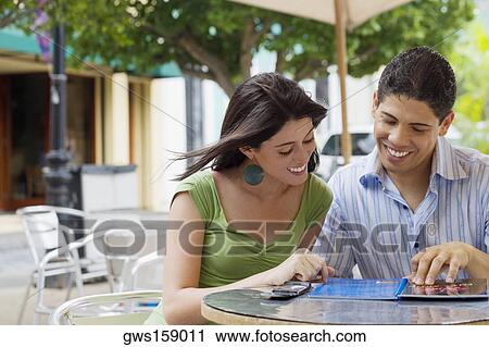 Stock Image - Close-up of a teenage girl and a young man reading a menu at a restaurant. Fotosearch