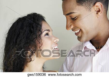 Stock Photograph - Close-up of a young couple looking at each other and smiling. Fotosearch