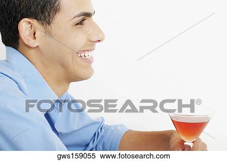 Stock Photography - Close-up of a young man holding a glass of martini. Fotosearch
