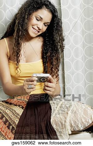 Stock Image - Close-up of a young woman holding a digital camera. Fotosearch