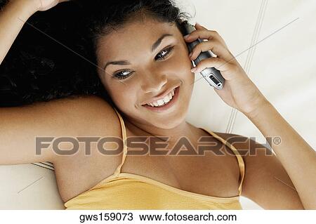 Close-up of a young woman lying on her back and talking on a mobile phone View Large Photo Image Stock Image - Close-up of a young woman lying on her back and talking on a mobile phone. Fotosearch