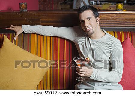 Portrait of a mid adult man sitting on a couch and holding a cocktail View Large Photo Image Stock Image - Portrait of a mid adult man sitting on a couch and holding a cocktail. Fotosearch