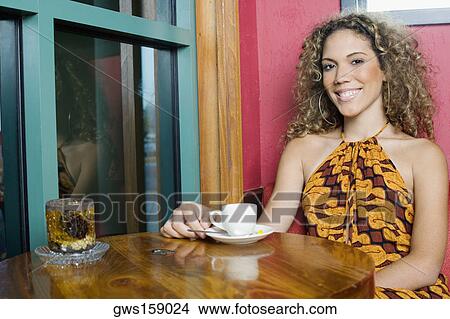 Picture - Portrait of a teenage girl sitting at a table with a cup of coffee. Fotosearch