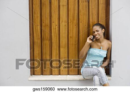 Stock Image - Portrait of a teenage girl smiling and talking on a mobile phone. Fotosearch