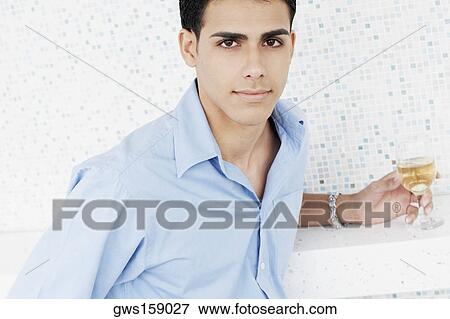 Portrait of a young man holding a glass of wine View Large Photo Image Stock Photo - Portrait of a young man holding a glass of wine. Fotosearch