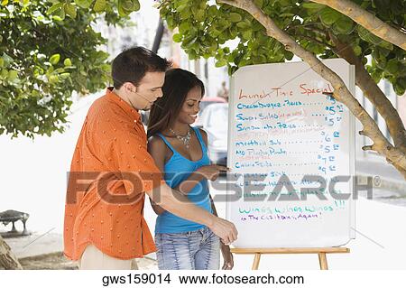 Side profile of a mid adult man and a teenage girl looking at a menu View Large Photo Image Picture - Side profile of a mid adult man and a teenage girl looking at a menu. Fotosearch
