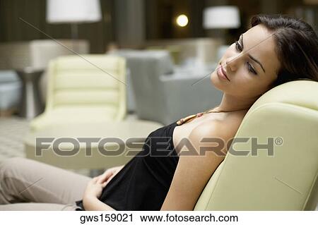Side profile of a young woman sitting on a chair View Large Photo Image Stock Image - Side profile of a young woman sitting on a chair. Fotosearch