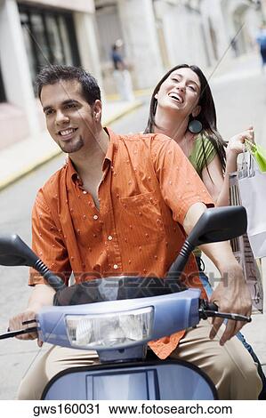 Stock Image - Close-up of a mid adult man and a teenage girl riding a scooter. Fotosearch