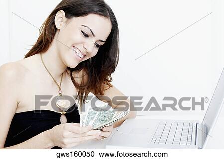 Close-up of a young woman counting dollar bills in front of a laptop View Large Photo Image Stock Image - Close-up of a young woman counting dollar bills in front of a laptop. Fotosearch