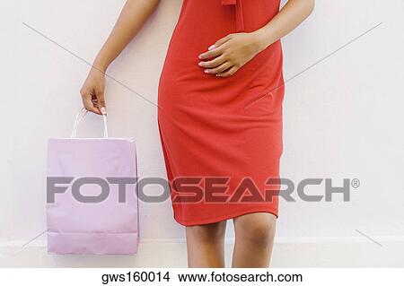Picture - Mid section view of a teenage girl holding a shopping bag. Fotosearch