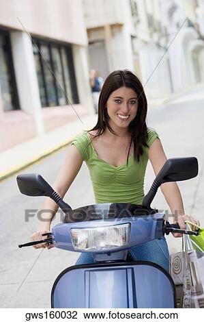 Stock Image - Portrait of a teenage girl riding on a scooter. Fotosearch