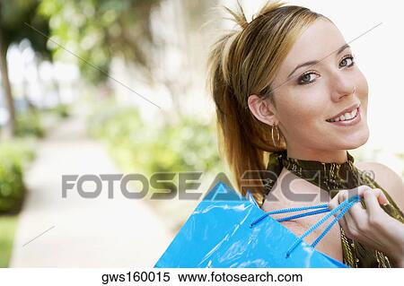 Portrait of a young woman holding a shopping bag View Large Photo Image Stock Photography - Portrait of a young woman holding a shopping bag. Fotosearch