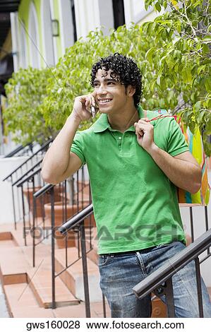 Young man using a mobile phone and smiling View Large Photo Image Stock Photo - Young man using a mobile phone and smiling. Fotosearch