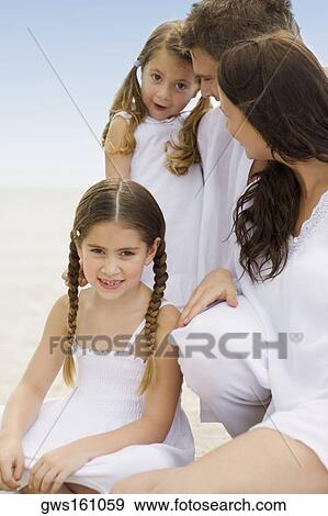 Close-up of a young couple and their two daughters sitting on the beach View Large Photo Image Stock Photo - Close-up of a young couple and their two daughters sitting on the beach. Fotosearch