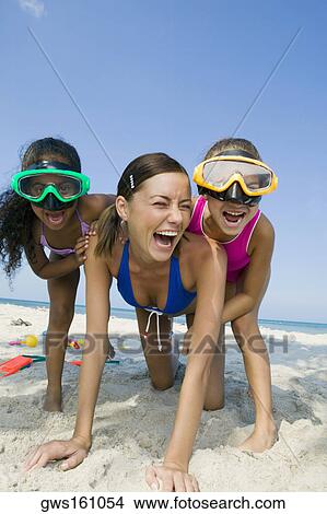 Picture - Close-up of a young woman playing with two girls on the beach. Fotosearch