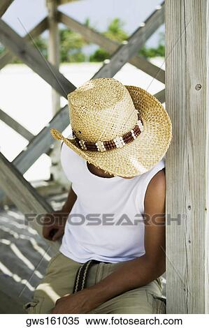 High angle view of a young man wearing a straw hat and sitting under a pier View Large Photo Image Stock Photography - High angle view of a young man wearing a straw hat and sitting under a pier. Fotosearch