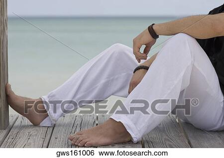 Low section view of a young woman sitting on the pier View Large Photo Image Stock Photograph - Low section view of a young woman sitting on the pier. Fotosearch