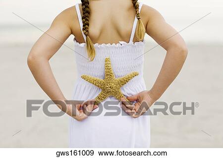 Mid section view of a girl standing on the beach and holding a starfish View Large Photo Image Stock Photo - Mid section view of a girl standing on the beach and holding a starfish. Fotosearch
