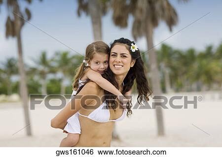 Stock Photograph - Portrait of a girl riding piggyback on her mother. Fotosearch