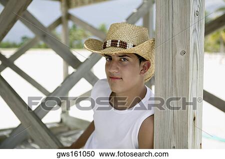Portrait of a teenage boy sitting and wearing a straw hat View Large Photo Image Stock Image - Portrait of a teenage boy sitting and wearing a straw hat. Fotosearch