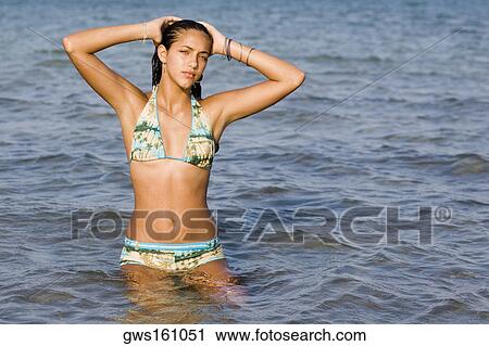 Stock Image - Portrait of a teenage girl standing in water in the sea. Fotosearch