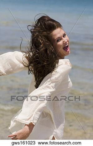 Portrait of a young woman on the beach with her arms outstretched View Large Photo Image Stock Image - Portrait of a young woman on the beach with her arms outstretched. Fotosearch
