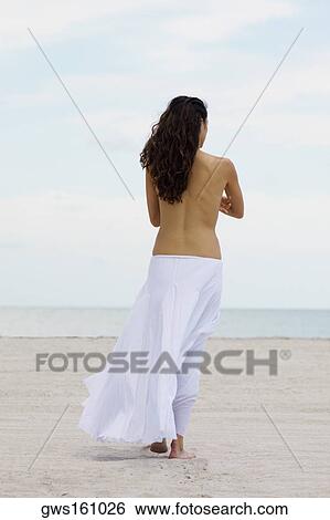 Rear view of a woman walking on the beach View Large Photo Image Stock Photograph - Rear view of a woman walking on the beach. Fotosearch