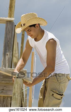 Side profile of a teenage boy building a wooden structure View Large Photo Image Picture - Side profile of a teenage boy building a wooden structure. Fotosearch