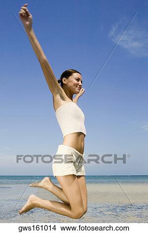Side profile of a young woman jumping on the beach View Large Photo Image Picture - Side profile of a young woman jumping on the beach. Fotosearch