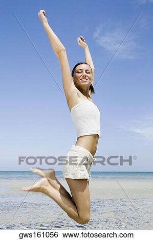 Side profile of a young woman jumping on the beach View Large Photo Image Stock Photograph - Side profile of a young woman jumping on the beach. Fotosearch