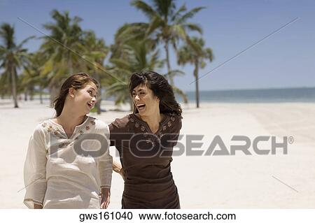 Two young women looking at each other and laughing View Large Photo Image Stock Image - Two young women looking at each other and laughing. Fotosearch