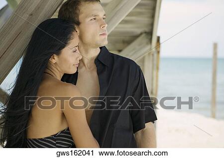 Close-up of a young couple standing on the beach and looking away View Large Photo Image Stock Image - Close-up of a young couple standing on the beach and looking away. Fotosearch