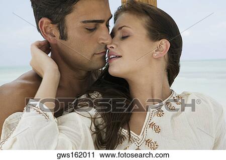 Stock Image - Close-up of a young woman and a mid adult man embracing each other. Fotosearch