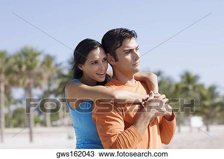 Close-up of a young woman embracing a mid adult man from behind View Large Photo Image Stock Image - Close-up of a young woman embracing a mid adult man from behind. Fotosearch
