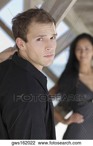 Portrait of a young man with a young woman in the background View Large Photo Image Stock Image - Portrait of a young man with a young woman in the background. Fotosearch