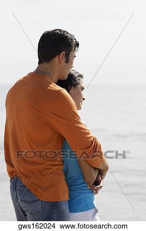 Side profile of a mid adult man embracing a young woman from behind View Large Photo Image Picture - Side profile of a mid adult man embracing a young woman from behind. Fotosearch