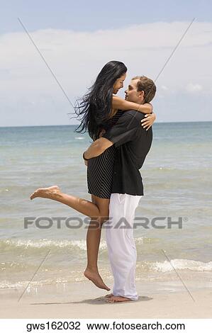 Side profile of a young couple embracing each other on the beach View Large Photo Image Stock Image - Side profile of a young couple embracing each other on the beach. Fotosearch