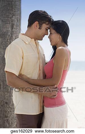 Side profile of a young woman and a mid adult man embracing each other on the beach View Large Photo Image Stock Photo - Side profile of a young woman and a mid adult man embracing each other on the beach. Fotosearch