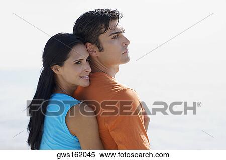 Side profile of a young woman embracing a mid adult man from behind View Large Photo Image Stock Photography - Side profile of a young woman embracing a mid adult man from behind. Fotosearch