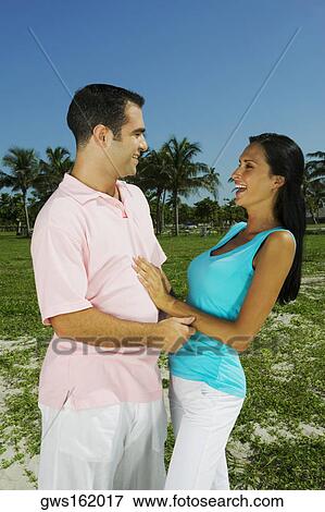 Stock Photo - Young couple looking at each other and smiling. Fotosearch