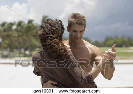 Stock Image - Close-up of a young couple dancing on the beach. Fotosearch