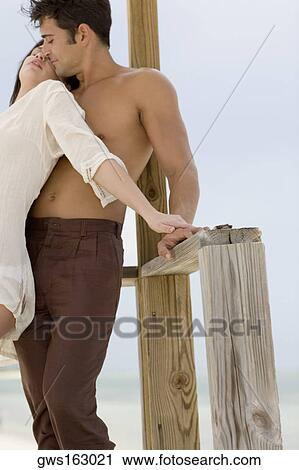 Close-up of a young couple standing on a pier View Large Photo Image Stock Image - Close-up of a young couple standing on a pier. Fotosearch