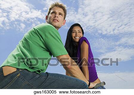Stock Photography - Low angle view of a young couple looking away. Fotosearch