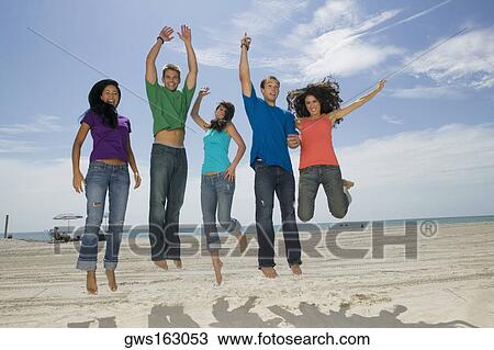 Low angle view of three young women and two young men jumping on the beach View Large Photo Image Stock Image - Low angle view of three young women and two young men jumping on the beach. Fotosearch