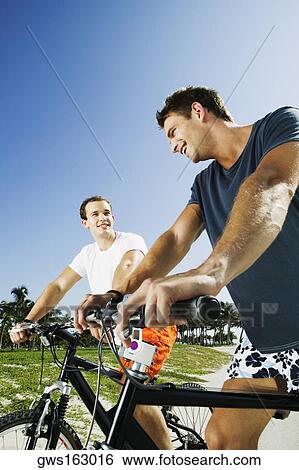 Stock Photograph - Low angle view of two young men on bicycles. Fotosearch